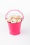 Heap pumpkin seeds in pink bucket on white background