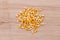 Heap of raw corns seeds, maize or sweetcorn kernels top view on wooden background.