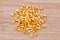 Heap of raw corns seeds, maize or sweetcorn kernels top view on wooden background.