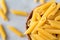 Heap raw penne pasta on ultimate gray background