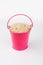 Heap rice grains in pink bucket on white background