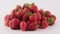 Heap of ripe strawberries rotate on a white background