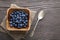 Heap ripe sweet blueberries and spoon on wooden table top view