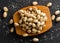 Heap of salted, roasted green pistachio nuts snack in wooden bowl on black background with sea salt, healthy food snack