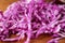 Heap of shredded fresh red cabbage on wooden table, closeup