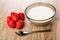 Heap of strawberries, brown bowl with yogurt, teaspoon on wooden table