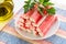 Heap of surimi crab sticks with parsley on a white saucer over a striped table mat near olive oil glass jar. Seafood and