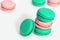 Heap of sweet macaroons of blue and pink color close-up on a white background. French almond biscuits