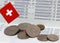 Heap of Swiss franc coin money and mini Switzerland flag on the book bank