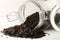 Heap of uncooked, raw, black wild rice grains in glass storage jar on white table background