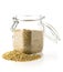 Heap of uncooked, raw freekeh or firik, roasted wheat grain, in glass storage jar over white