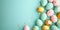 Heap of various pastel colors painted easter eggs with golden decorations on turquoise background. Greeting card, banner format