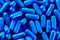 Heap of vivid blue capsule pills close up background