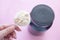 Heap of whey protein powder with plastic spoon on a female hand and a can of protein in the background on pink