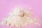 Heap of whey protein powder with plastic spoon on a light pink background
