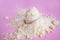 Heap of whey protein powder with plastic spoon on pink background