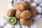 Heap of whole and cut fresh kiwis on beige table, above view