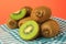 Heap of whole and cut fresh kiwis on orange background, closeup