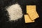 Heap of whole grain organic flour and yellow cracker on black