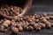 Heap whole organic grains of black pepper on wooden table with c