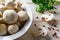 Heap of whole raw fresh champignons in a white bowl, bunch of parsley and pepper on a wooden table. Mushrooms as vegetable protein