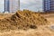 heaps of dry clay on construction site, preparation for landscaping, in background facade work on residential buildings