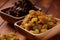 Heaps of yellow and dark Raisins, in a wooden bowls.