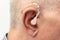 Hearing aid in the ear of aged old man