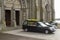 A hearse and a funeral car parked outside a church in ireland