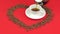 Heart of coffee beans on a red background. Pouring coffee into a cup.