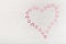 Heart consisting of small pink hearts on a light wooden background