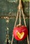 Heart cut into red apple hanging from string