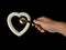 Heart with a door handle on a black background. The white heart opens with a hand. Concept: closed heart