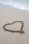 Heart drawn on the beach sand with sea foam and wave, angled