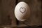 heart is drawn on a chicken egg that lies on forks on an old wooden table, love