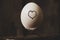Heart is drawn on a chicken egg that lies on forks on an old wooden table, love