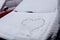 Heart drawn on the hood of a snow-covered car, close - up-the concept of the arrival of cold winter days