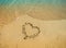 Heart drawn on the sand with sea water near it