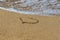 Heart drawn on wet sand beach. Part of the heart is washed away by a wave. Symbol of the beginning or the end of love