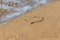 Heart drawn on wet sand beach. Part of the heart is washed away by a wave. Symbol of the beginning or the end of love