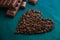 Heart from fragrant coffee beans on a dark wooden background wit