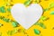 Heart frame with tropical leaves cut from paper in the sun rays on a yellow background. Summer concept