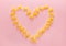 Heart frame from wheat pasta farfalle on rose background. Valentine`s day.