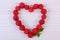 Heart of fresh raspberries on white wooden table, symbol of love