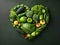 Heart of green fruits and vegetables isolated on dark green background. Green life concept and healthy eating lifestyle. Shape of