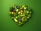 Heart of green fruits and vegetables isolated on green background. Green life concept and healthy eating lifestyle. Shape of heart