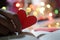 Heart in hand. Red love shaped paper on bright colorful bokeh background. Blank paper with hope and love symbol in hands. Copy