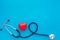 Heart health, health care concept. Stethoscope near rubber heart on blue background top view space for text