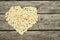 The heart is laid out of pumpkin seeds close-up on a wooden table. Place for the inscription. Unusually, creatively