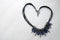 Heart laid out of a woman`s jewelry, necklaces with black threads, blue jewels, diamonds, diamonds in the shape of a heart